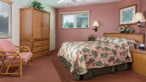 Un dormitorio con cama, armario de madera, una silla, ventana con persianas y una lámpara de pared.