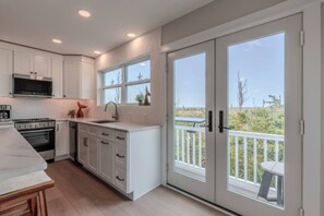 A modern kitchen with white cabinets, a built-in oven, and a large window overlooking a balcony. - •Bay Views• Close to Cape May & Wildwoods • (Middle Township)