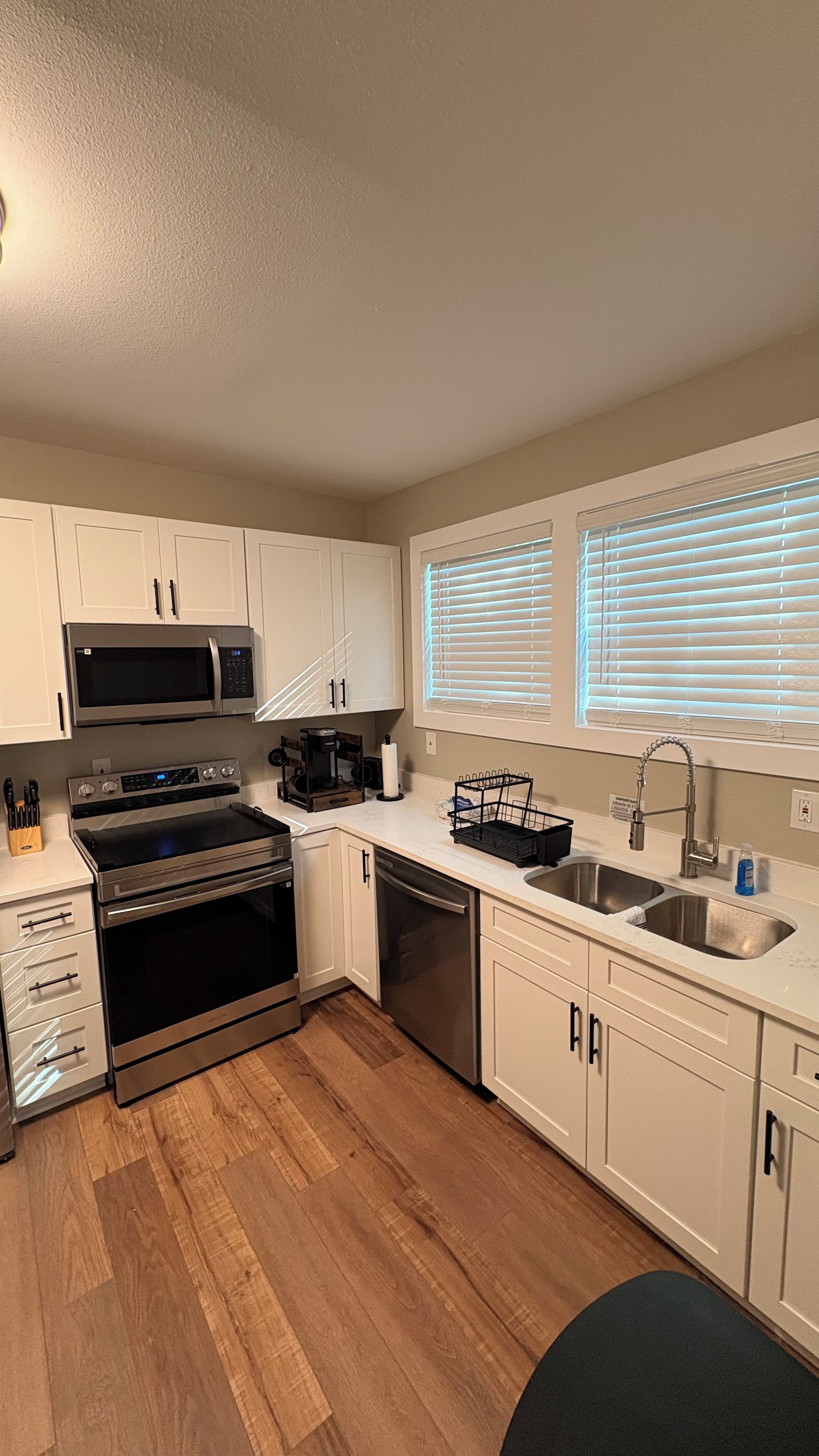 A modern kitchen with white cabinets, stainless steel appliances, a dishwasher, and a sink.