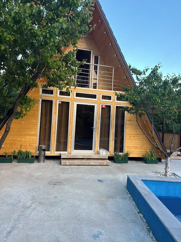 A modern wooden house with a large glass door and windows, a concrete driveway, and a small tree in the foreground. - Getamej Eco Villa & Pool (Getamej)