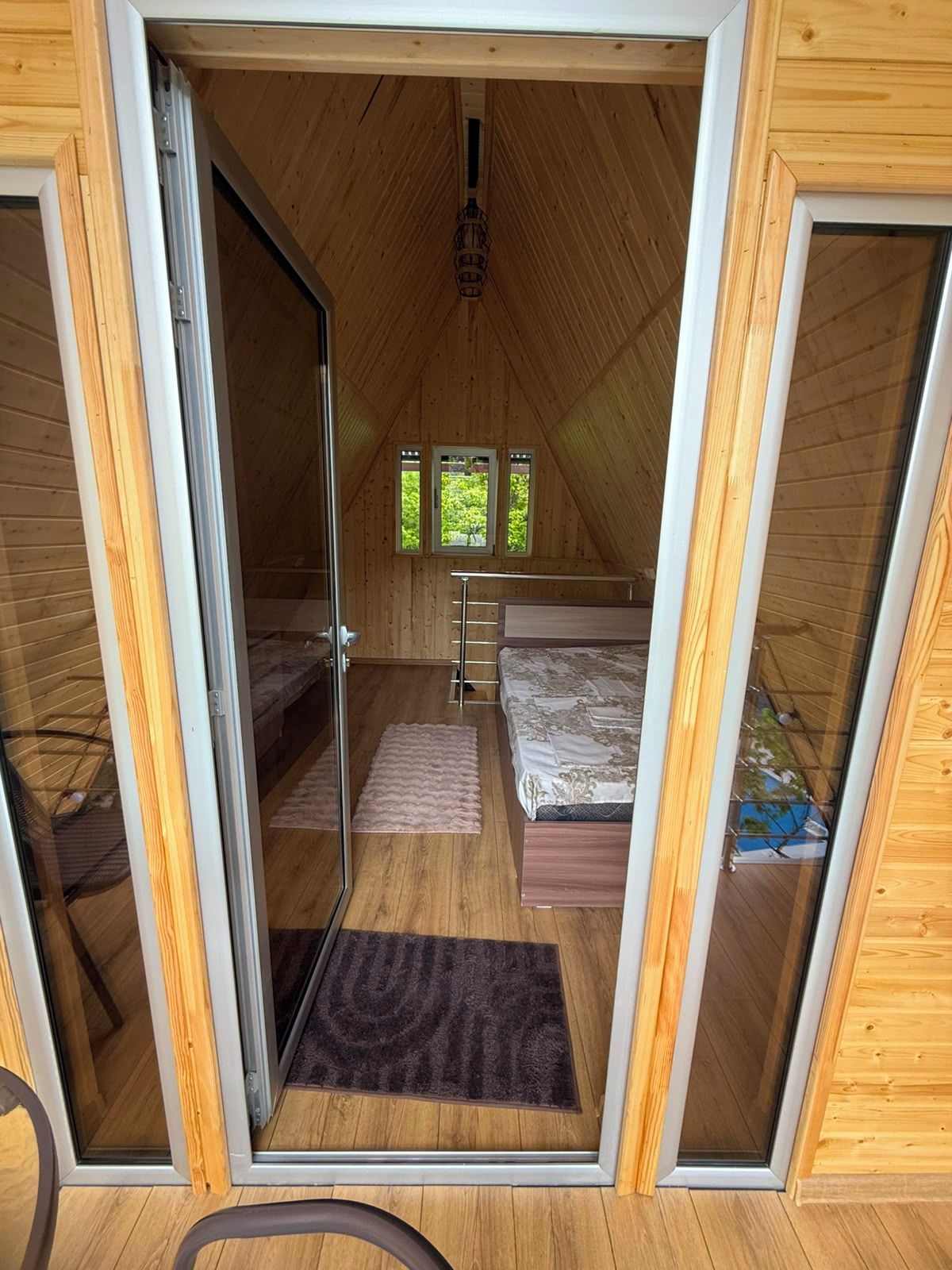 Quarto de sótão acolhedor com cama, uma pequena janela e teto de madeira.