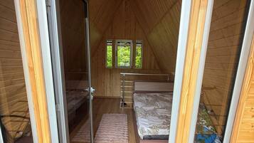 Quarto de sótão acolhedor com cama, uma pequena janela e teto de madeira.