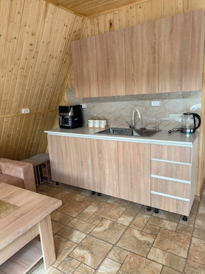 A compact kitchen with wooden cabinets, a sink, a coffee maker, and a bench. - Getamej Eco Villa & Pool (Getamej)