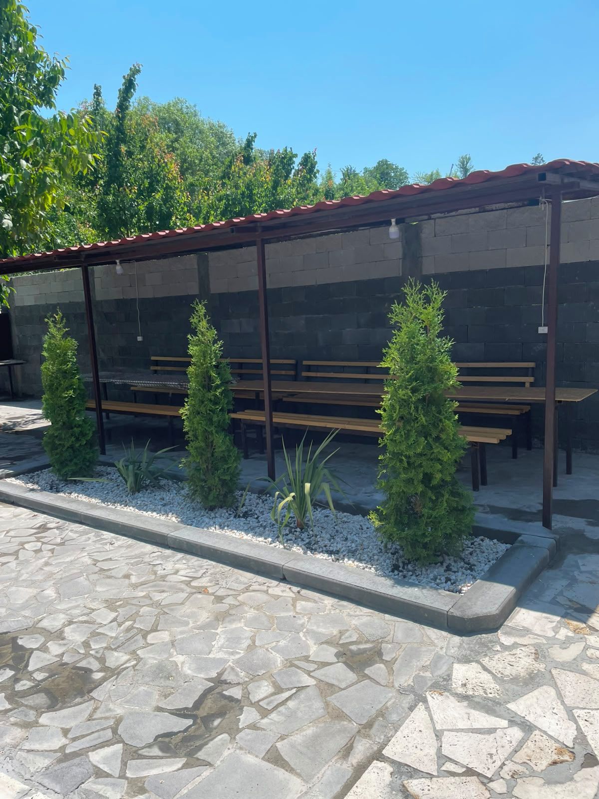 A covered outdoor seating area with benches and potted plants.