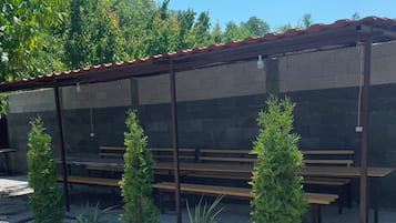 A covered outdoor seating area with benches and potted plants.