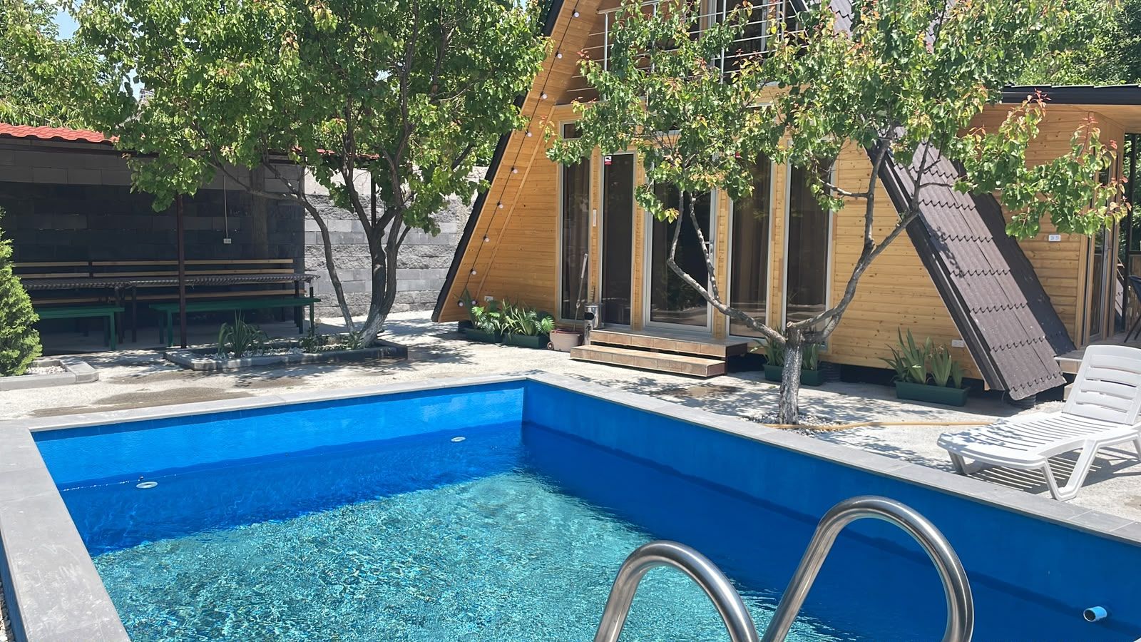 Piscina com água azul cristalina, rodeada por um deck de madeira e uma espreguiçadeira.