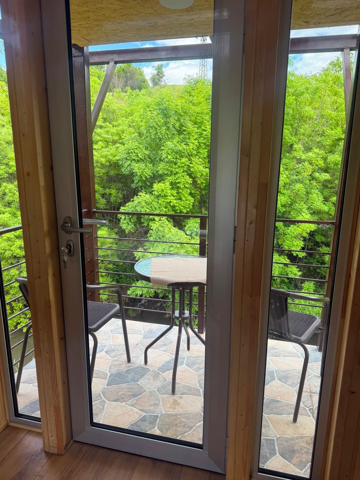 Puerta de cristal que da a un patio exterior con una mesa redonda y sillas.