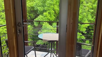 Puerta de cristal que da a un patio exterior con una mesa redonda y sillas.
