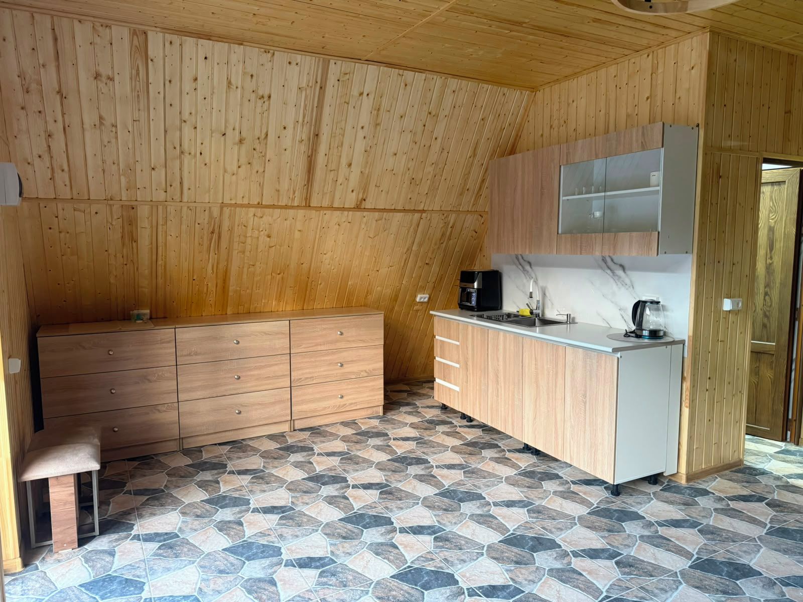 A compact kitchen with wooden cabinetry, a countertop, and a stone-patterned floor.