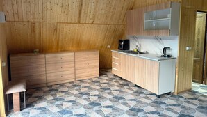 A compact kitchen with wooden cabinetry, a countertop, and a stone-patterned floor. - Getamej Eco Villa & Pool (Getamej)