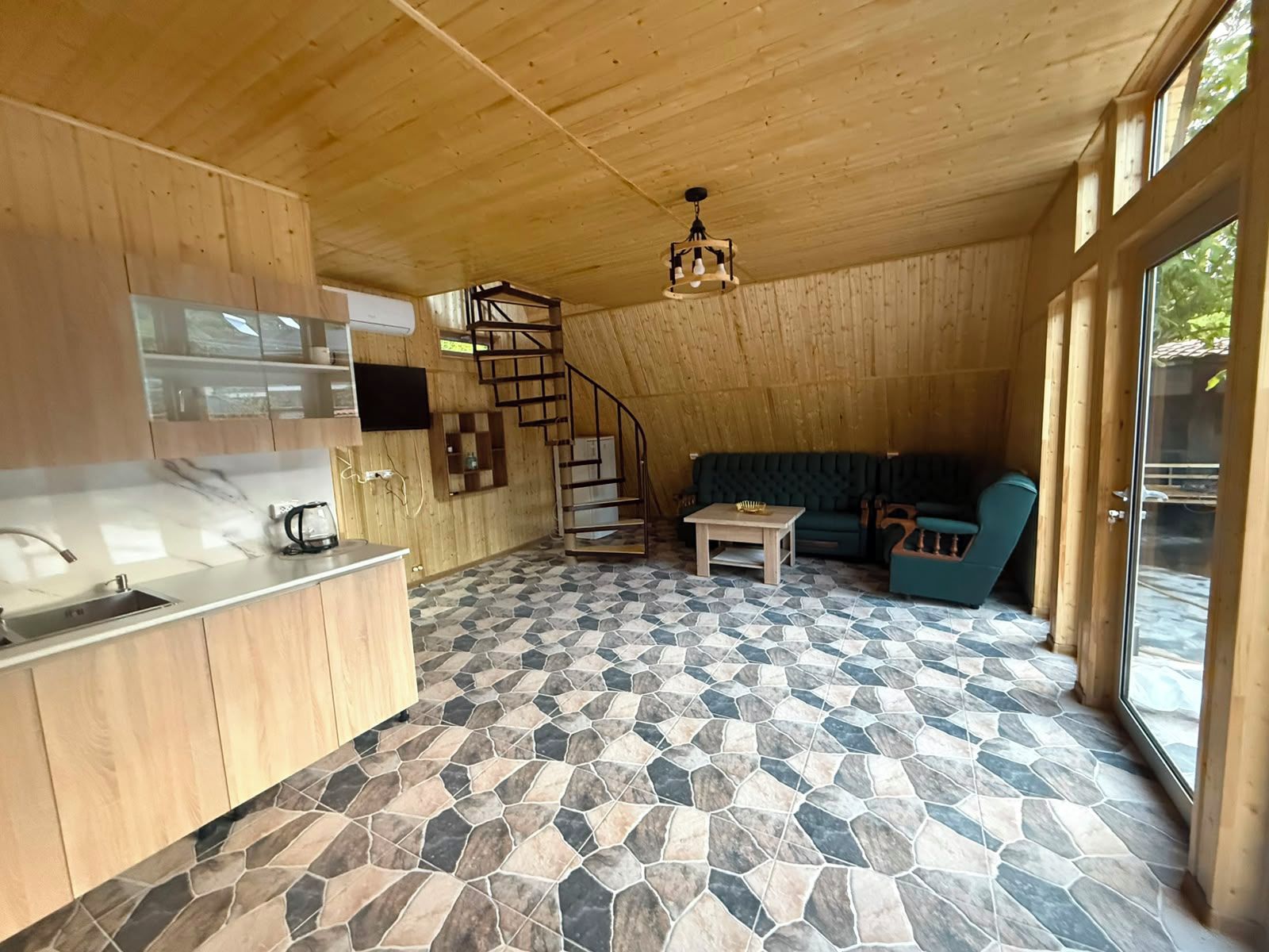 A wooden interior with a kitchen, dining area, and a staircase.
