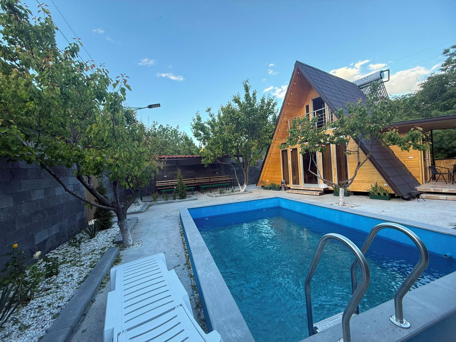 A modern house with a swimming pool, a covered patio, and a wooden deck.