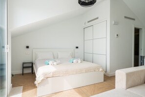 Ein modernes Schlafzimmer mit einem großen Bett, einem Nachttisch, einem Kleiderschrank und einer Sitzecke.