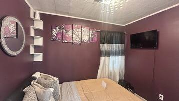 Una camera da letto con un letto, una TV, uno specchio e decorazioni alle pareti.