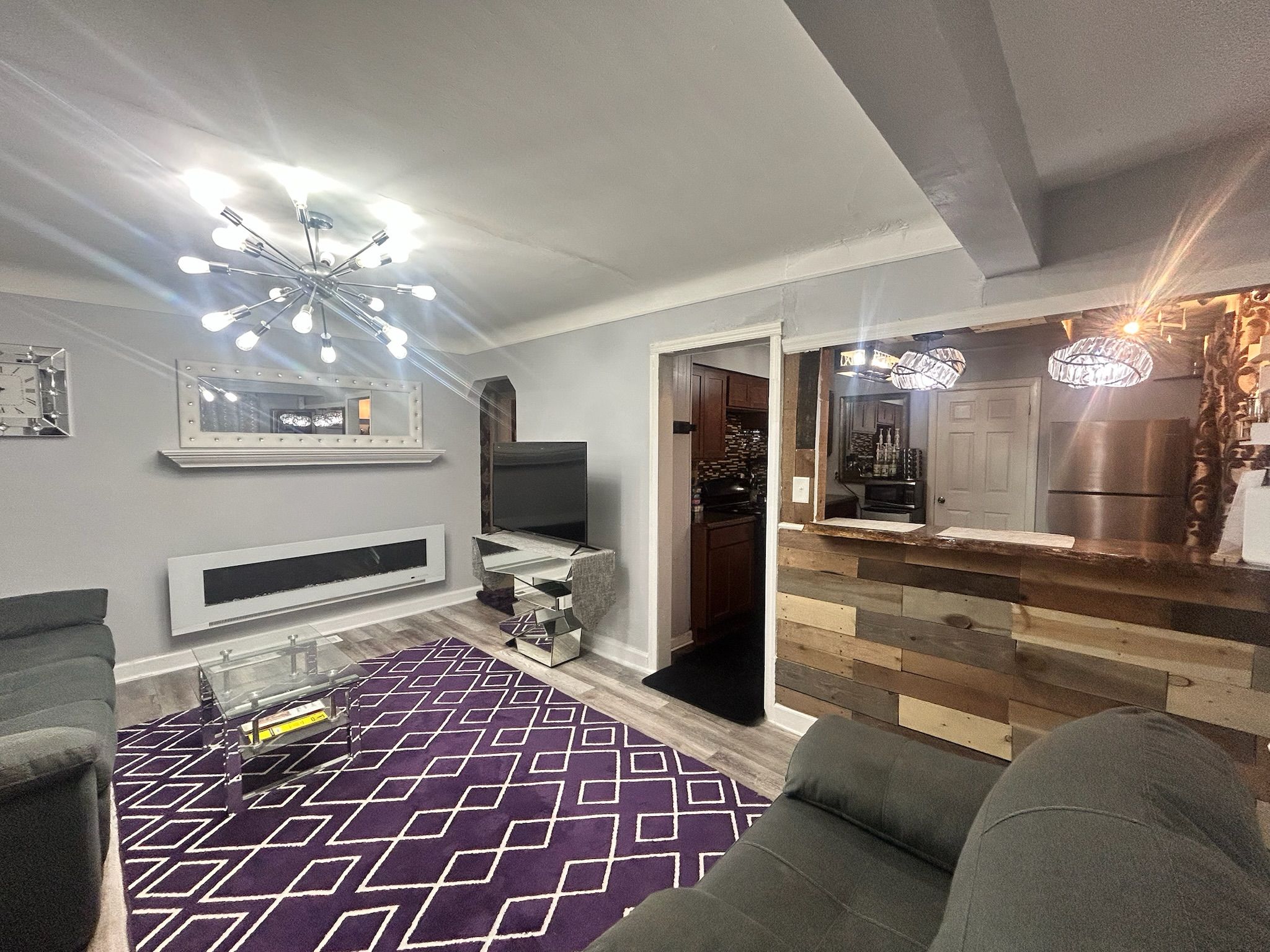 A modern living room with a sofa, a coffee table, a TV, and a patterned rug.