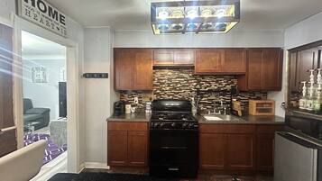 Cocina compacta con armarios de madera, estufa a gas y un resalte de ladrillo integrado.