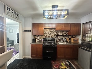 A compact kitchen with wooden cabinets, a gas stove, and a built-in brick backsplash.