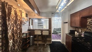 A compact kitchen with a dining area, a bar stool setup, and a sign that reads 'HOME IS WHERE THE HEART IS.' - Charming 2-bedroom house in superb Wyandotte with AC (Wyandotte)
