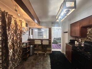Uma cozinha compacta com área de refeições, balcão e uma placa com a frase 'LAR É ONDE ESTÁ O CORAÇÃO'.