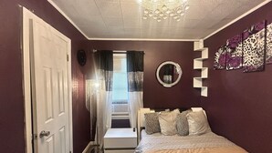 A bedroom with a bed, a door, a mirror, and a chandelier. - Charming 2-bedroom house in superb Wyandotte with AC (Wyandotte)