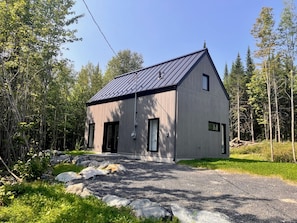 A modern two-story house with a sloped roof, large windows, and a stone pathway leading to the entrance. - Chalet with 2 bedrooms, 5 minutes from Mount Adstock. Skiing, golf, hiking (Adstock)