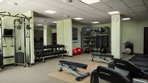 Uma academia com esteiras, halteres e aparelhos de musculação.