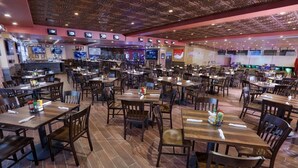 En rummelig restaurant med flere borde og stole, forskellige siddepladser og et moderne loftdesign.