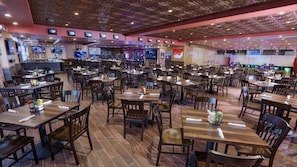 Un restaurant spacieux, doté de nombreuses tables et chaises, offrant différents types de sièges et caractérisé par un design moderne au niveau du plafond.