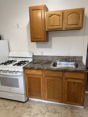 Una cocina con armarios de madera, una estufa blanca y una encimera de granito.