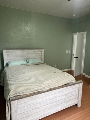 Un dormitorio con cama, una puerta y un interruptor de luz en la pared.
