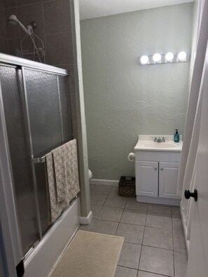 Un baño con cabina de ducha, lavamanos con espejo y perchero.
