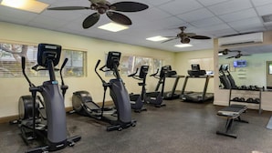 Une salle de sport équipée de tapis de course, de vélos elliptiques et d’un banc de musculation.