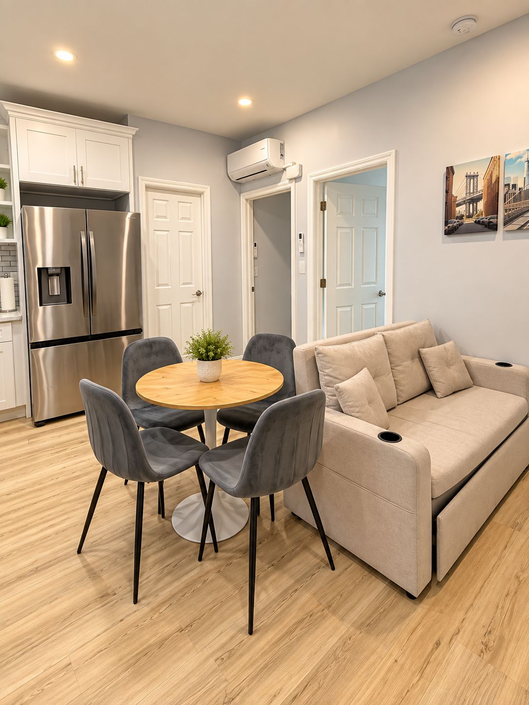 A modern kitchen with a built-in refrigerator, a dining table with chairs, and a beige sofa.