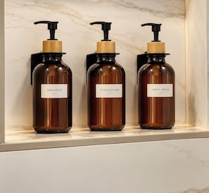 Three bottles of liquid soap on a shelf.