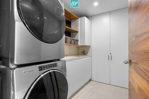 Una lavanderia funzionale con lavatrice e asciugatrice Whirlpool, un lavandino e una porta in legno.