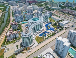 A modern hotel with a unique curved architecture, multiple swimming pools, and a well-maintained surrounding area. - Sirius Town Residence spa Luxury With Terrace (Antalya)