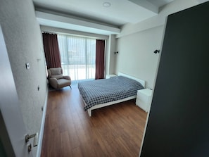 A bedroom with a bed, a chair, a bedside table, and a window with curtains. - Sirius Town Residence spa Luxury With Terrace (Antalya)