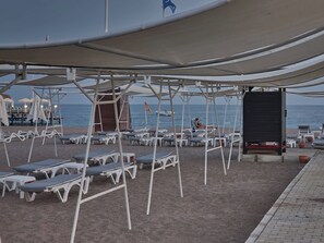 A beachside area with sun loungers and umbrellas, a lifeguard tower, and a view of the sea. - Sirius Town Residence spa Luxury With Terrace (Antalya)