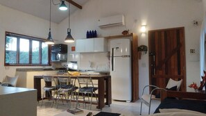 A compact kitchen with a refrigerator, microwave, and a dining area with chairs and a table. - House with ocean view in Ilhabela (Ilhabela)