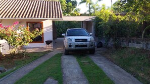 A vehicle parked in front of a house with a tiled roof and a paved driveway. - House with ocean view in Ilhabela (Ilhabela)