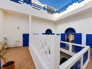 A courtyard with a white wall, blue doors, and a wooden floor.