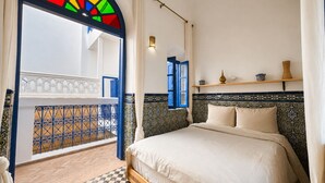 A bedroom with a bed, a window with blue shutters, a tiled floor, and a balcony with a railing. - Wonderful 3-bedroom riad with AC in charming Azemmour (Azemmour)