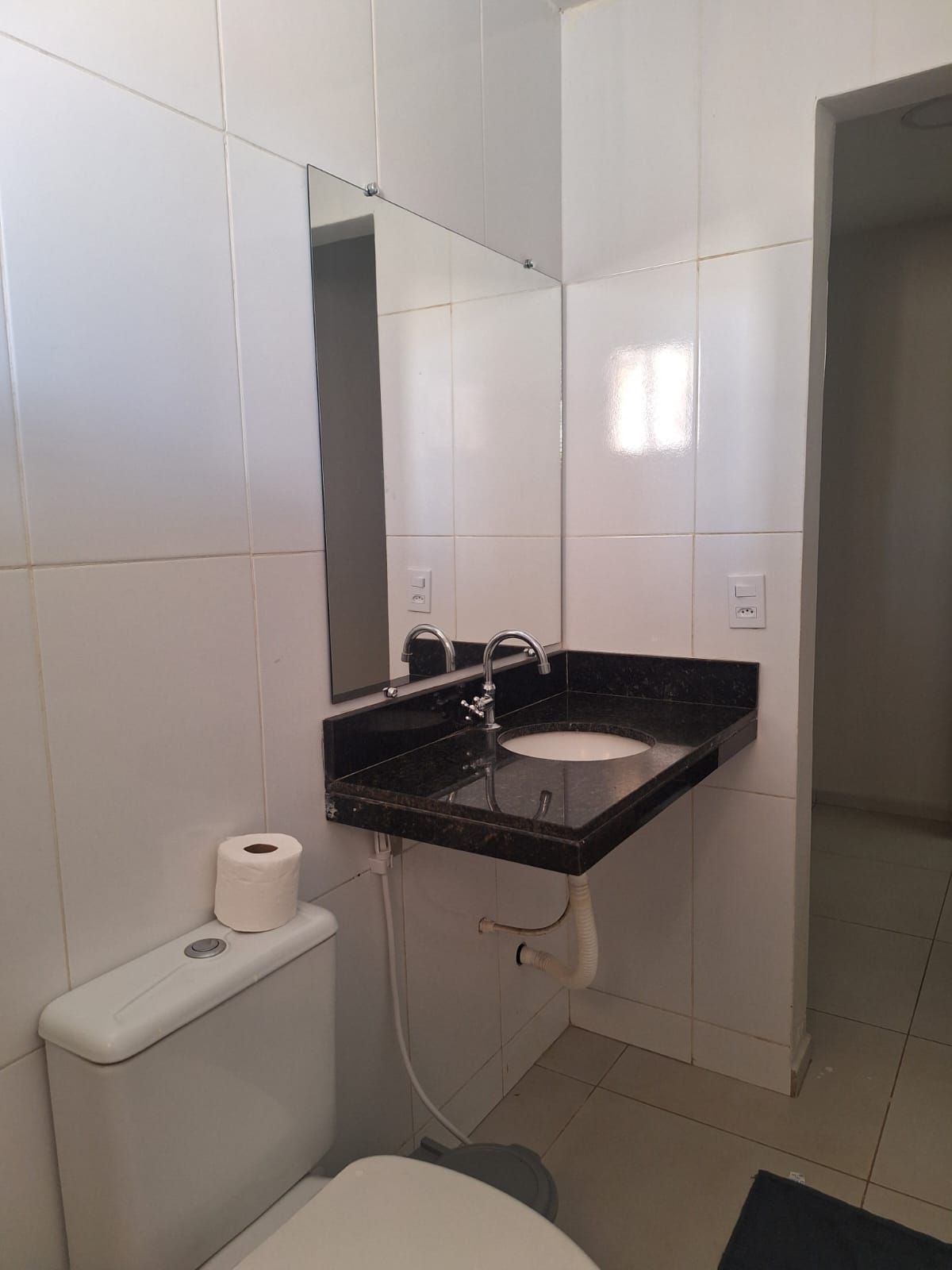 A bathroom with a white toilet, a black sink, and a mirror above the sink.