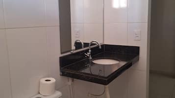 A bathroom with a white toilet, a black sink, and a mirror above the sink.