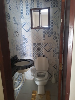 Et badeværelse med toilet, vask og et vindue.