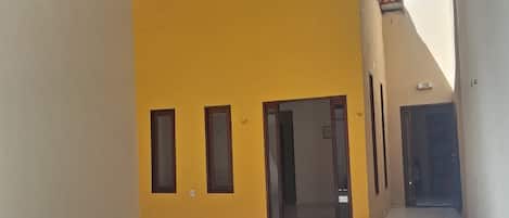 An open courtyard with a yellow wall and a tiled floor.