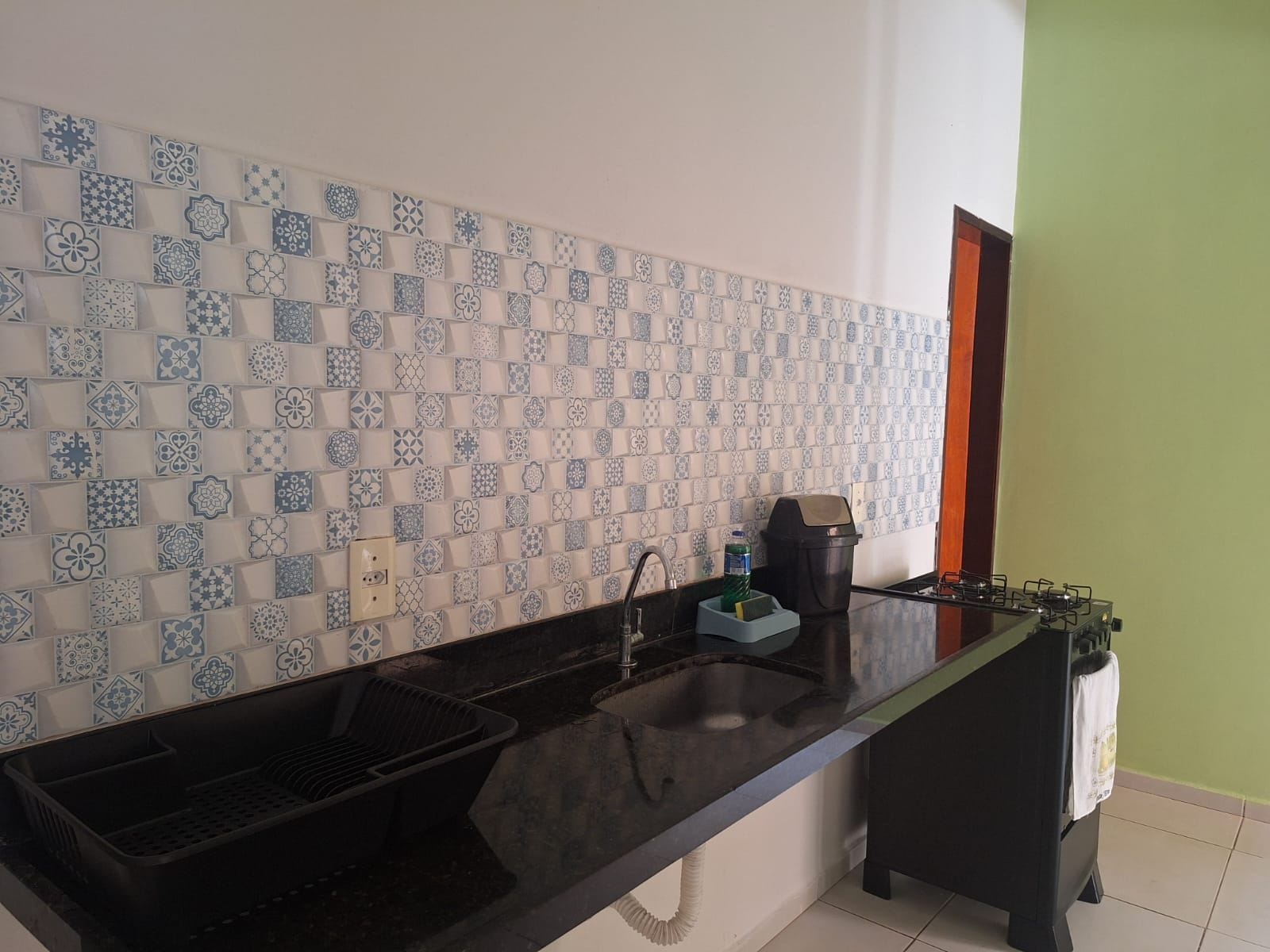 Una cocina con encimera negra, un fregadero y una estufa a gas.
