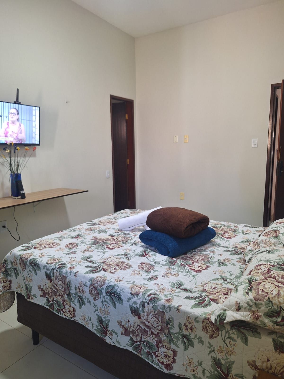 A bedroom with a bed, a television on the wall, and a door.