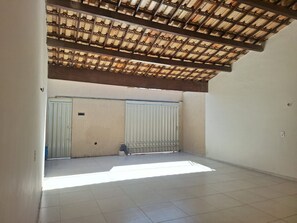 An interior space with a tiled floor, a ceiling with a wooden beam structure, and a white door with a metal gate.