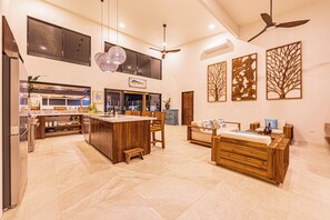A spacious kitchen with a central island, a dining area with wooden furniture, and a living space with a sofa and coffee table.